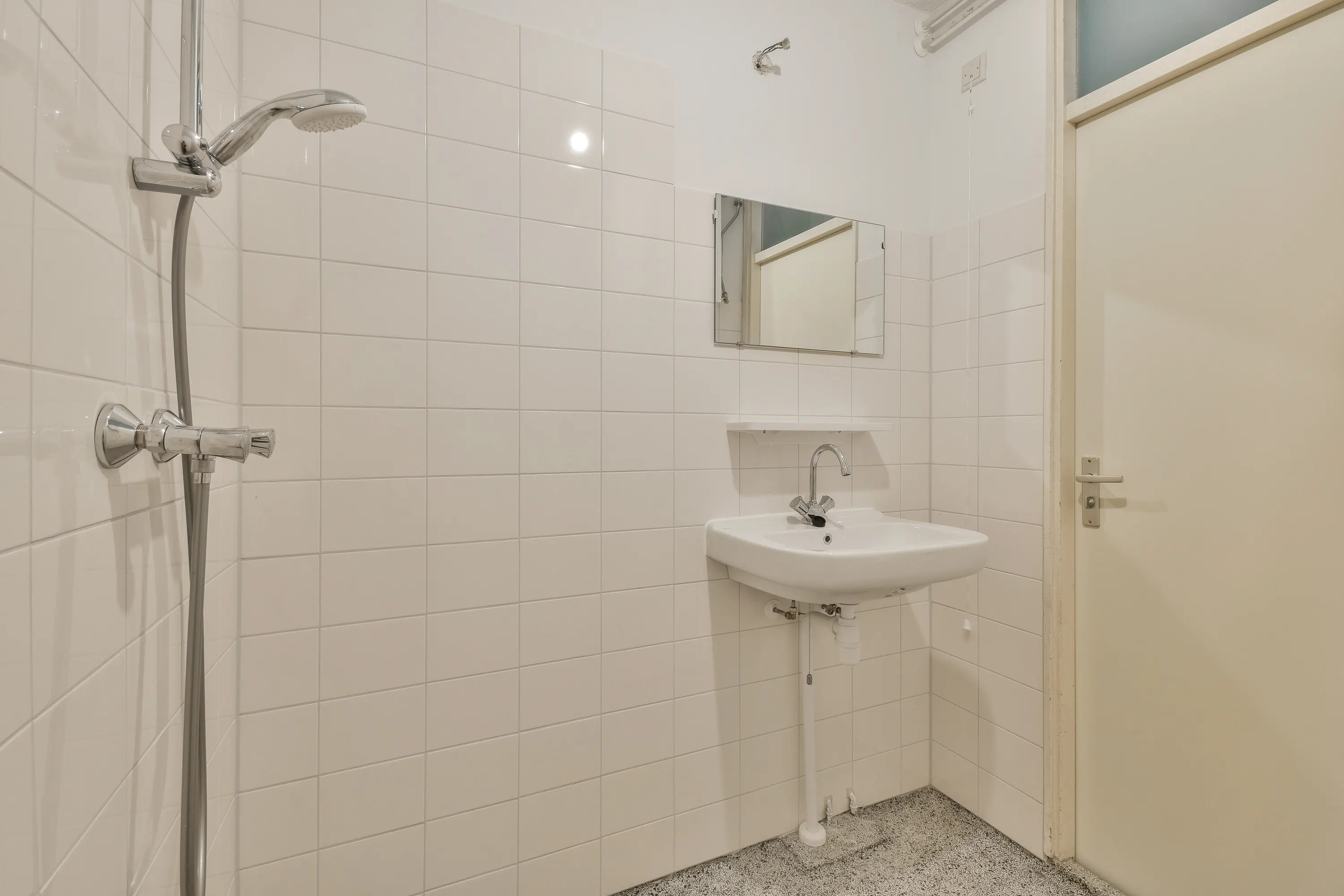 Badezimmer vor der Sanierung: alte Fliesen und einfaches Waschbecken