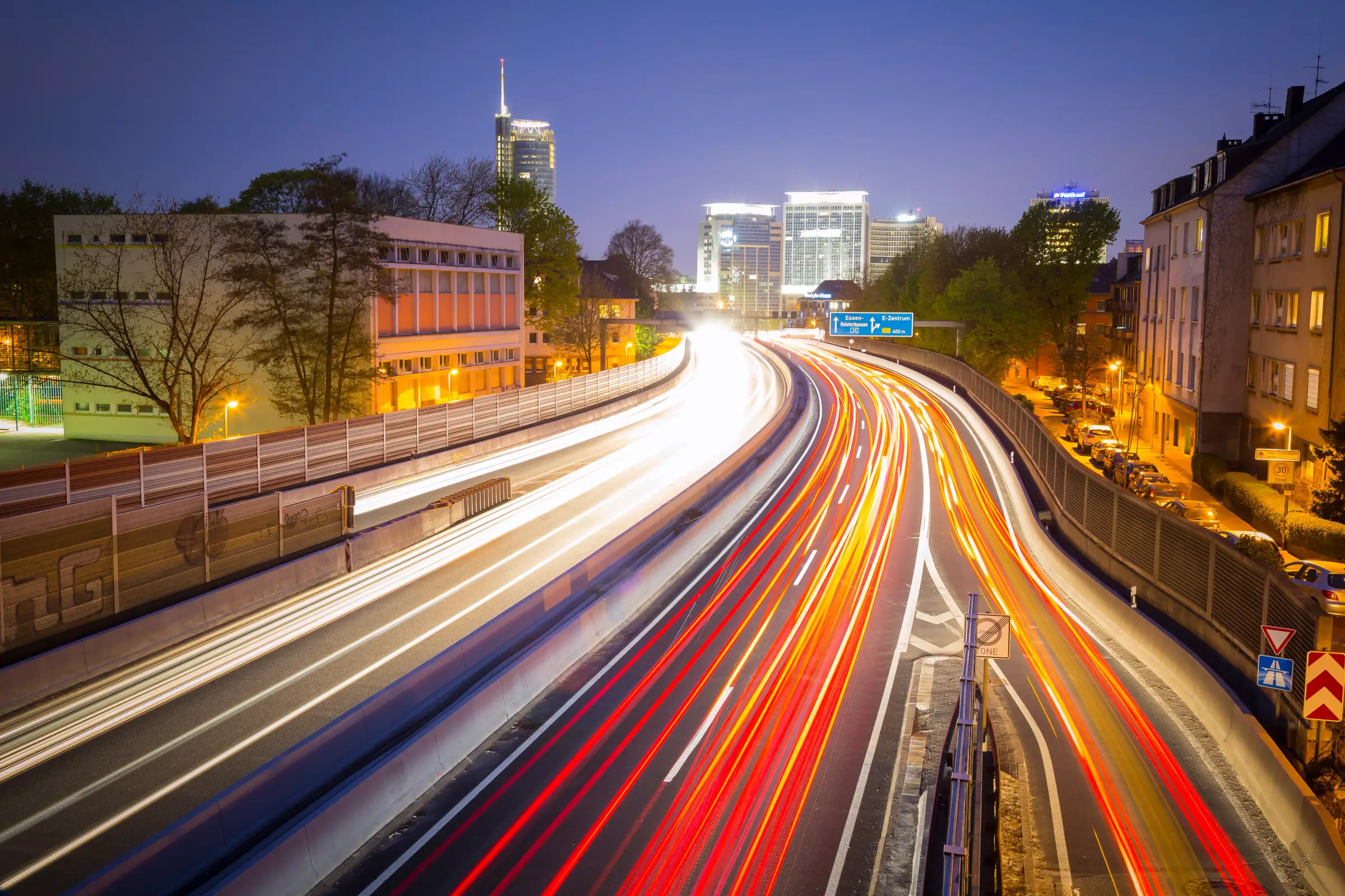 Essen bei Nacht: A40 mit Lichtspuren und Blick auf die Hochhäuser der Innenstadt