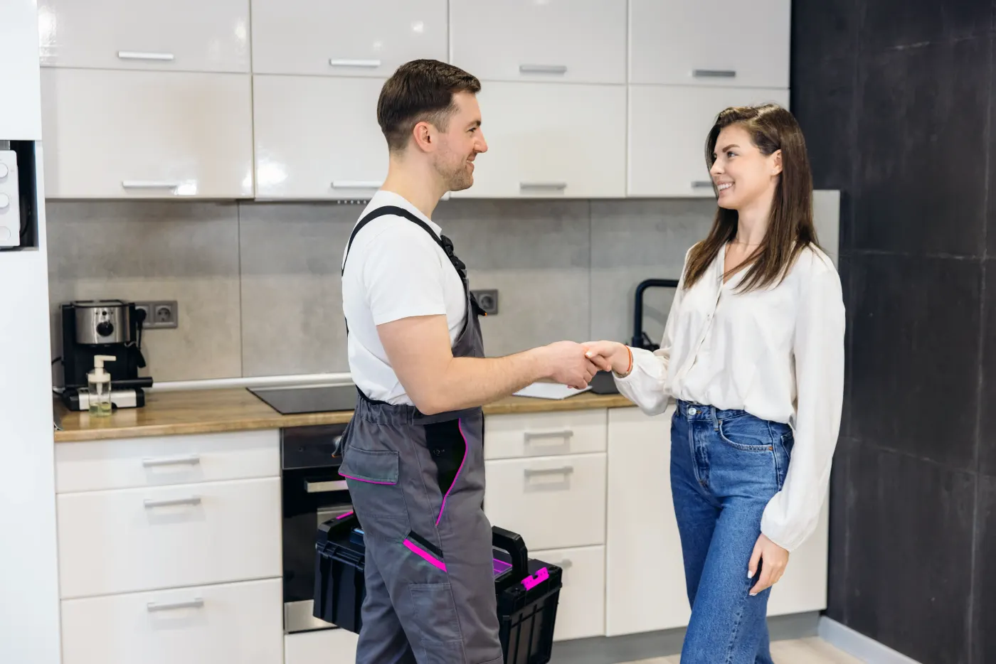 Handwerker und Kundin geben sich in der Küche die Hand